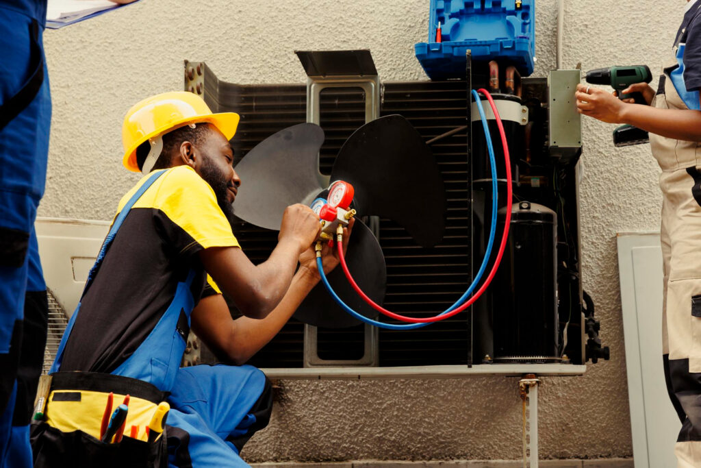 Technician servicing an air conditioning unit with gauges and tools, emphasizing HVAC repair and maintenance in Sparta.